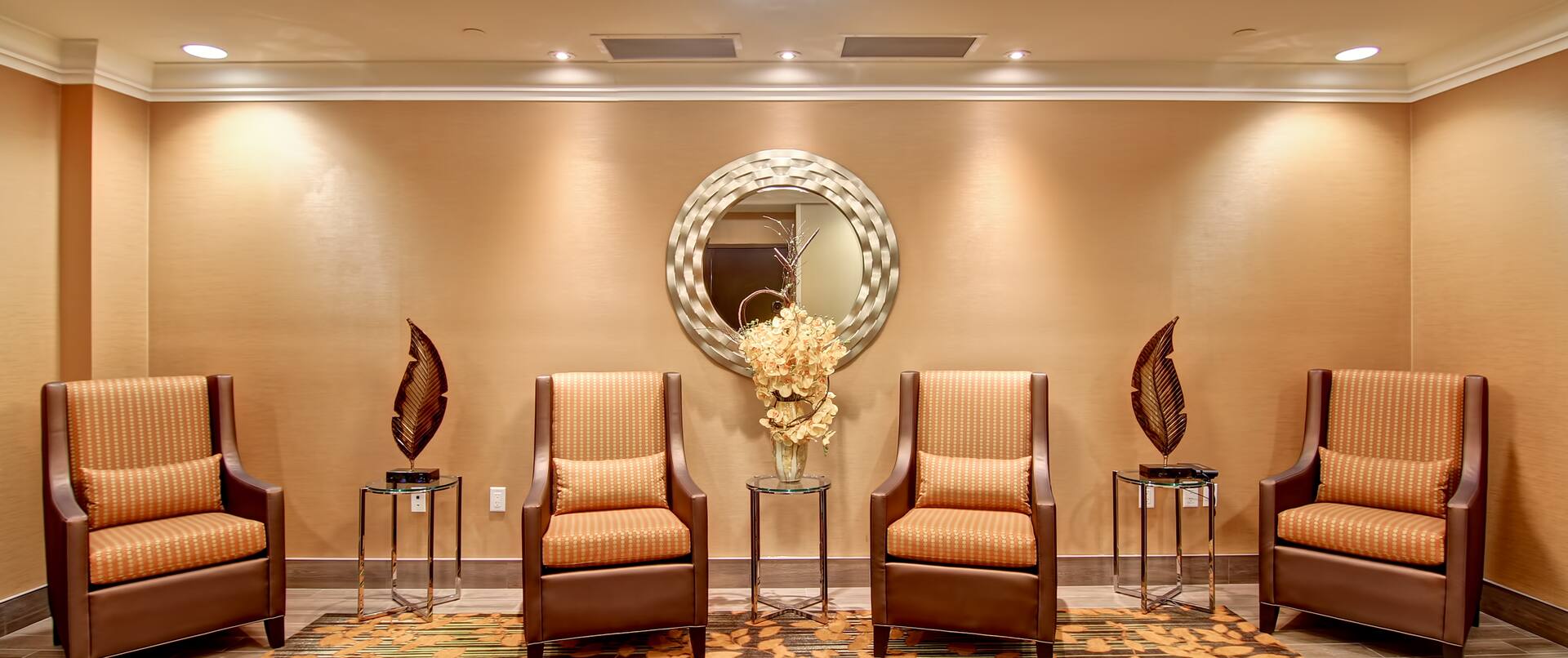 Four Armchairs and Three Tables in a Room With Round Wall Mirror