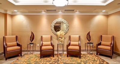 Four Armchairs and Three Tables in a Room With Round Wall Mirror