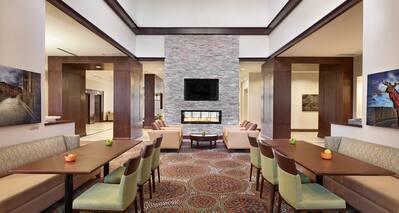 Booth Seating With Green Chairs in Breakfast Dining Area and View of Lounge Seating by Fireplace With TV