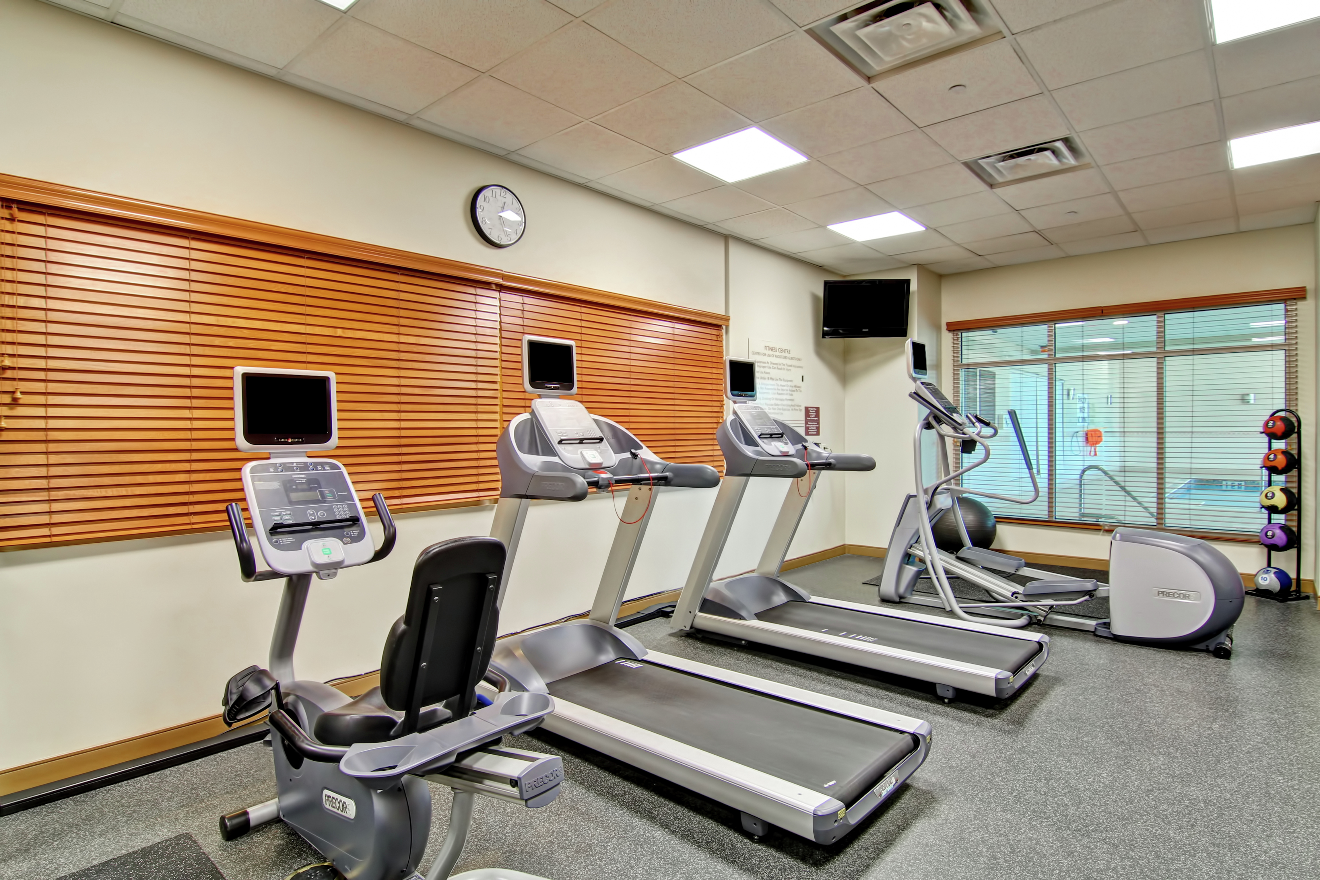 Fitness Center With Cardio Equipment, TV, Stability Ball, and Weight Balls by Window With View of Pool