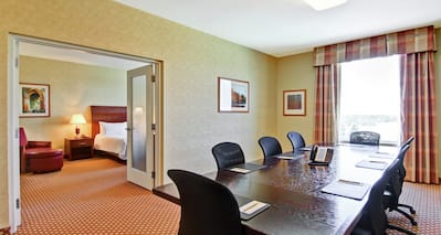 Boardroom Suite With Seating for 8, Window With Open Drapes, and Open Doorway to Bedroom