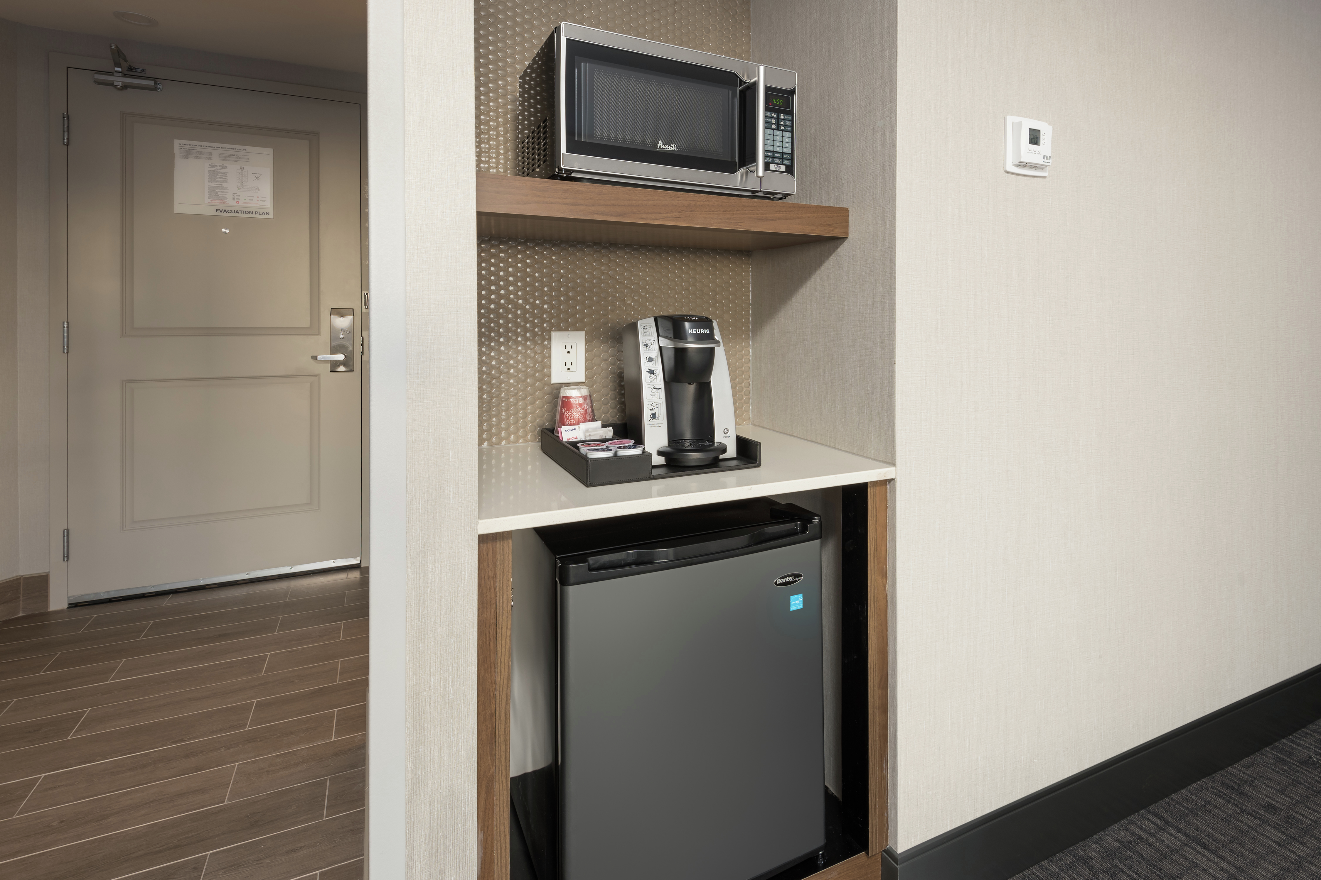 Espace de rangement ouvert révélant un réfrigérateur, un four à micro-ondes et une cafetière
