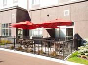 Outdoor Patio Seating With Red Umbrellas, Tables, and Chairs by Hotel Exterior
