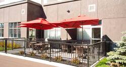 Outdoor Patio Seating With Red Umbrellas, Tables, and Chairs by Hotel Exterior