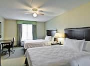 Ceiling Fan Above Two Queen Beds, Illuminated Lamp on Bedside Table, TV, Work Desk and Window With a View in Accessible Guest Room