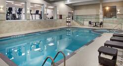 Indoor pool with hot tub, accessible ramp, stairs, view of fitness centre