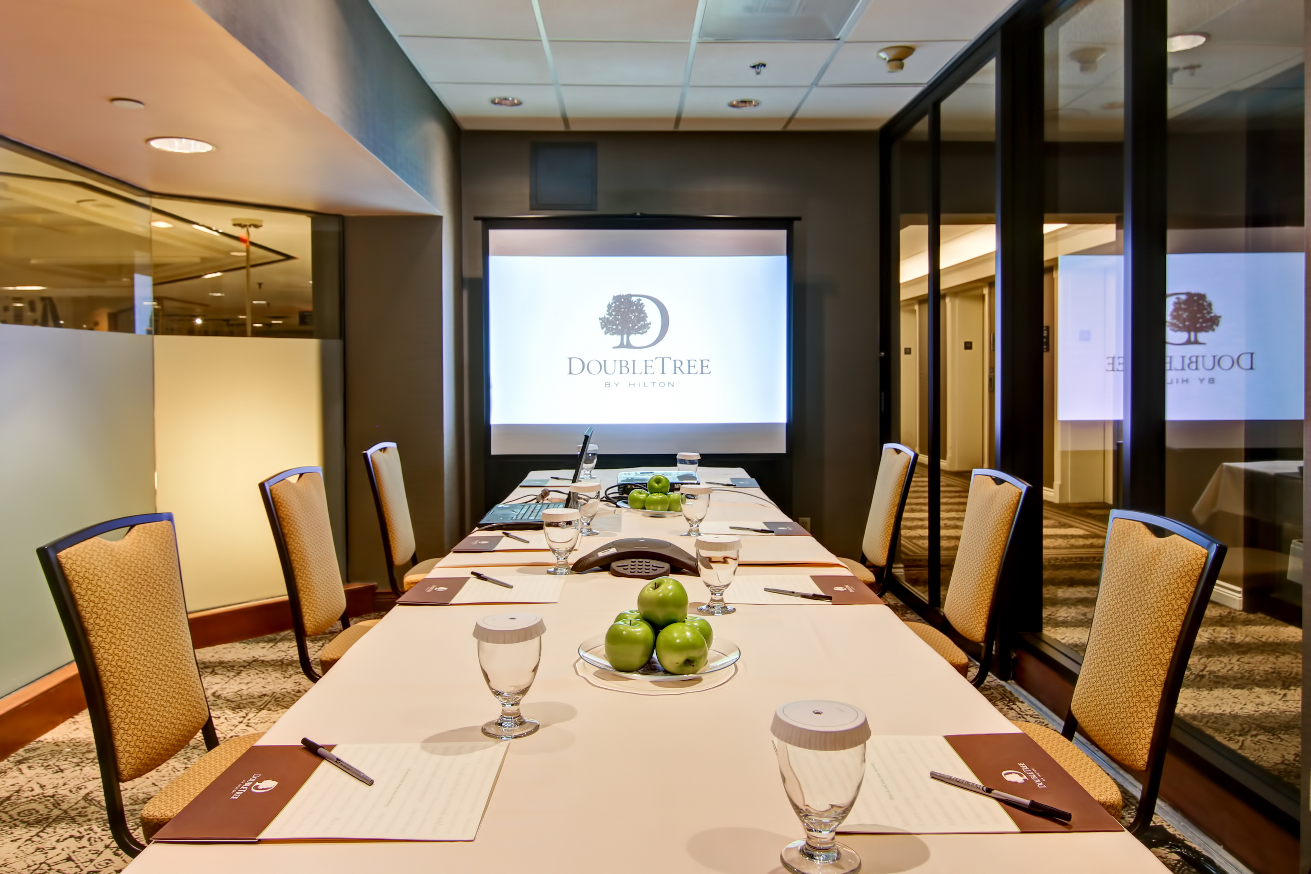 Small Conference Meeting Room with Seats, Projector Screen and Table with Notepads