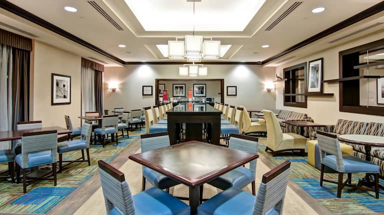 Espace social de l'hôtel avec longue table commune et chaises, et tables de repas avec des chaises