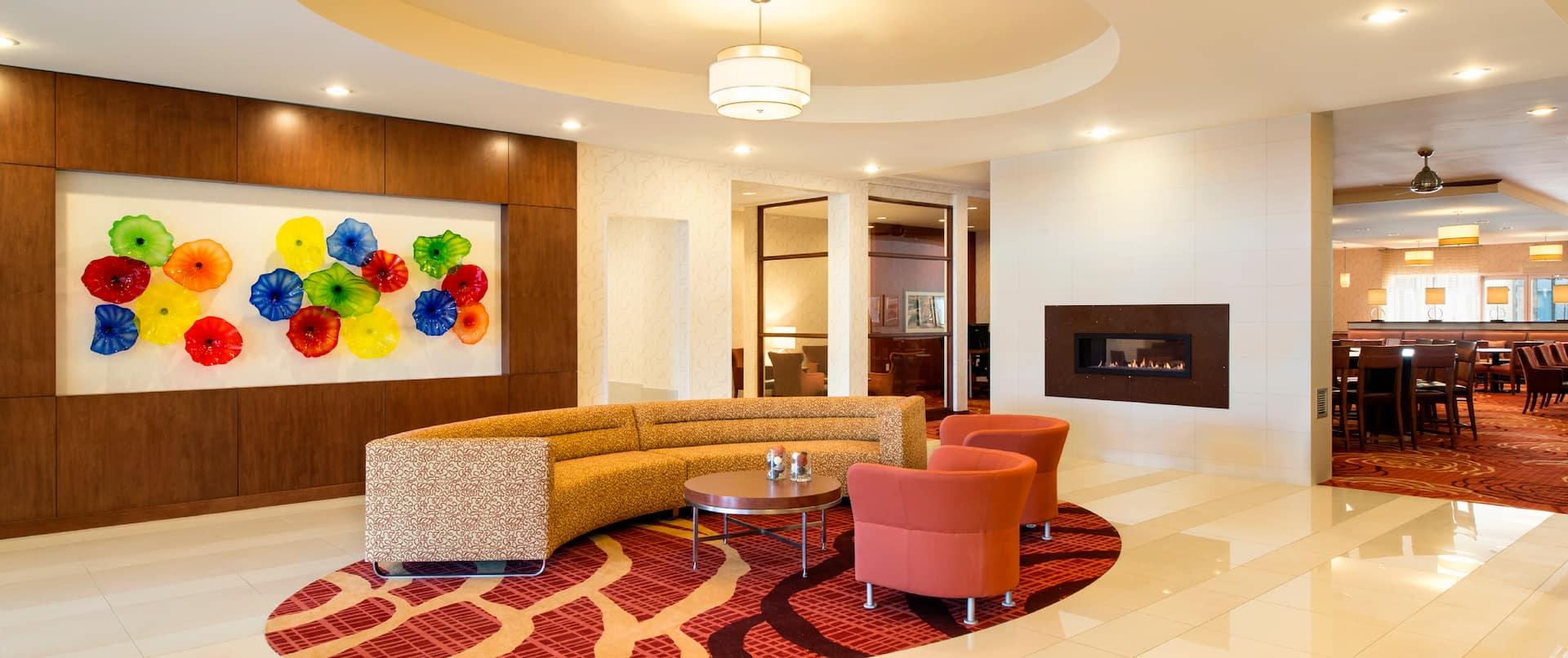 Soft Seating by Art Feature and Fireplace in Lobby Lounge Area With View of Dining Area