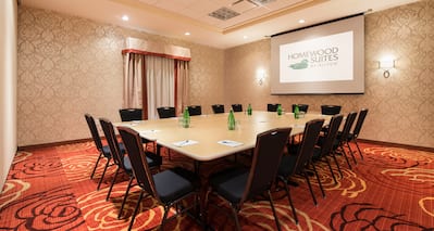 Square Table Setup With Seating for 16 Facing Presentation Screen in Meeting Room