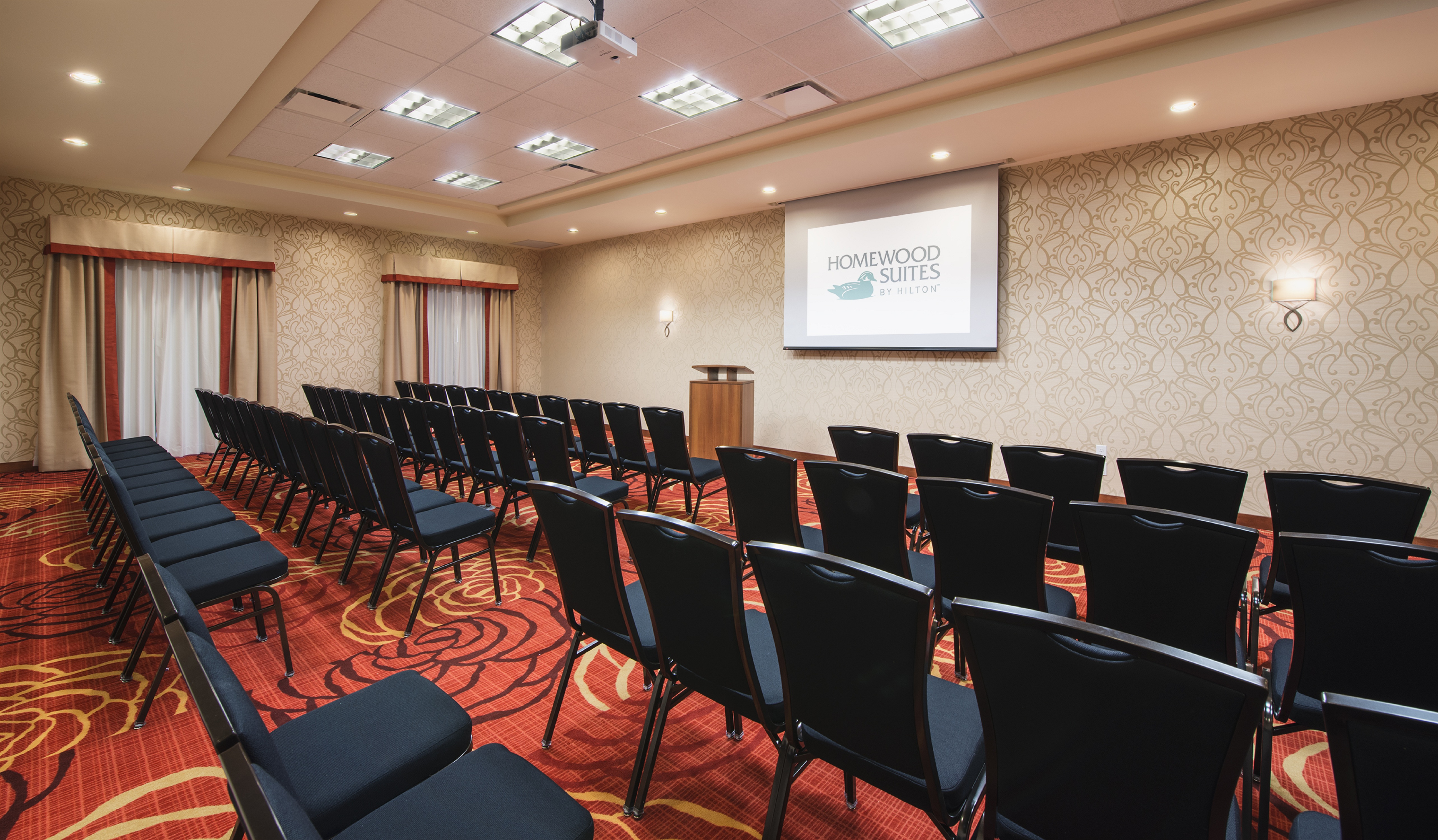 Meeting Room Arranged Theater Style With Chairs Facing Projector Screen and Podium