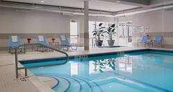  Indoor Pool With Loungers, Plants, Windows, and Chairs