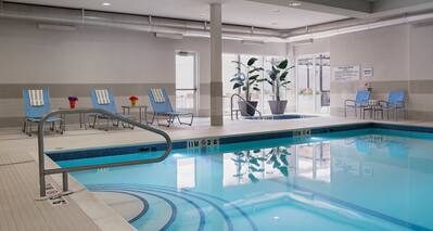  Indoor Pool With Loungers, Plants, Windows, and Chairs