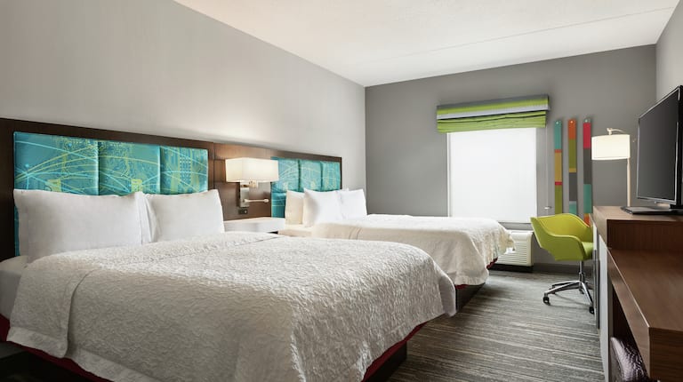 Two Queen Bed with Lamp and Table Between and In-room Amenities Across from End of Bed and Large Window