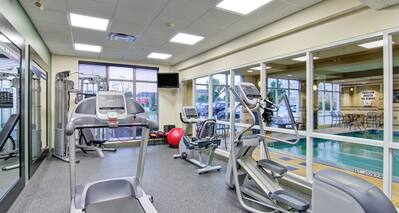 Fitness Center with Wall of Windows Providing a View to Indoor Pool Area