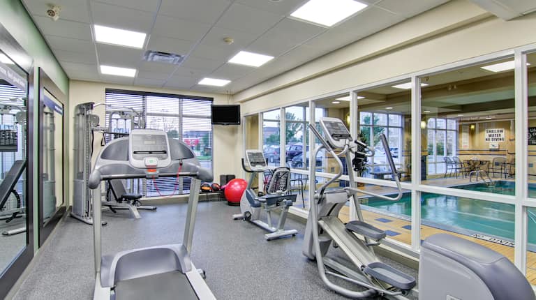 Fitness Center with Wall of Windows Providing a View to Indoor Pool Area