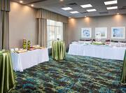 Waterfront Room Set Up for an Event With Tables Covered in Green and White Tablecloths