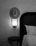 سرير داخل غرفة مع قبعة على الضوء وطاولة