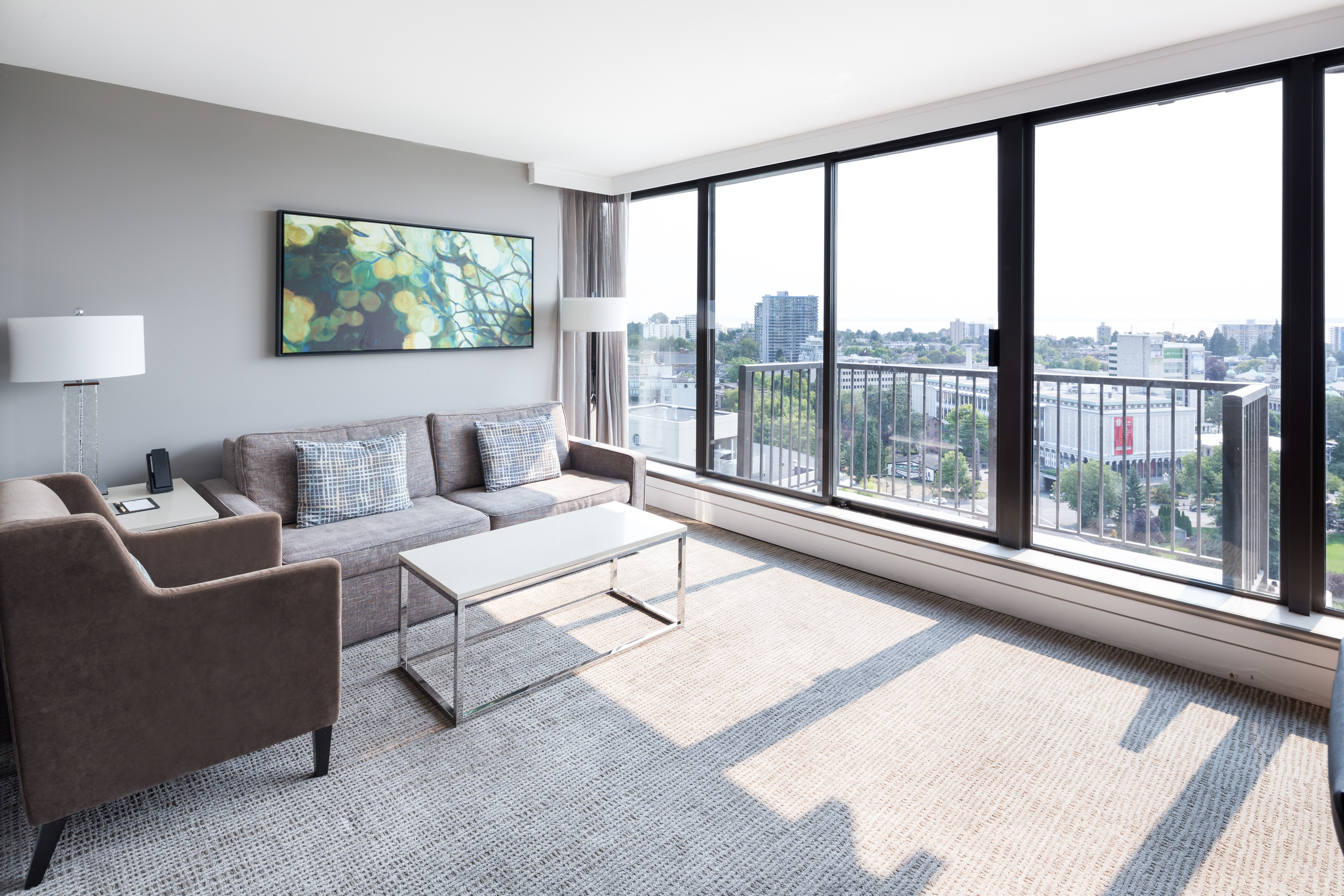  Living Room Suite Area With Sofa, Chair, Table, Floor Lamps and Floor to Ceiling Balcony Windows that Overlook the City