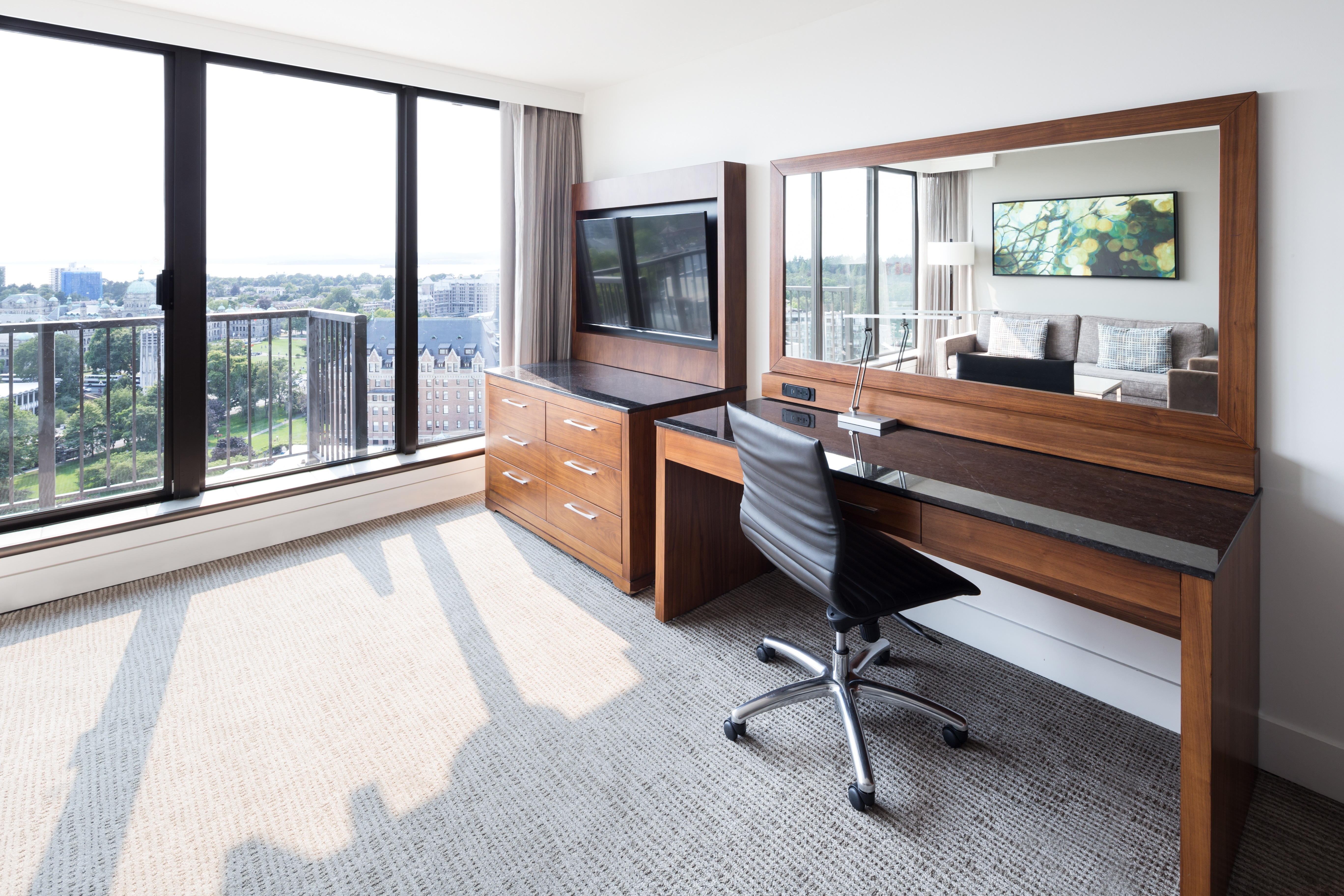 Desk, Wall Mounted Mirror, Rolling Chair, TV, Credenza by Window Balcony Overlooking the City in a Suite Room