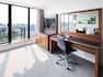 Desk, Wall Mounted Mirror, Rolling Chair, TV, Credenza by Window Balcony Overlooking the City in a Suite Room