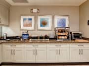 Wall Art, Signage, and White Cabinets, With Hot and Cold Buffet Selections on Counters of Breakfast Serving Area