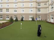 On-Site Putting Green With Blue and White Flags and a Golf Bag