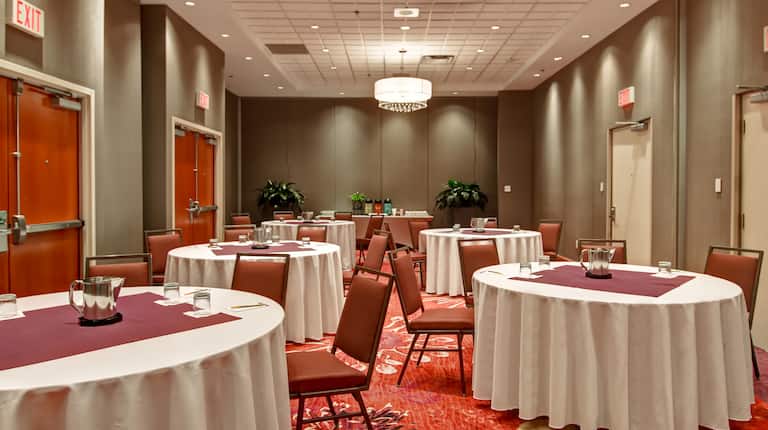 Banquet Room With Chairs, Round Tables With Water Pitchers, and Beverage Station in the Background