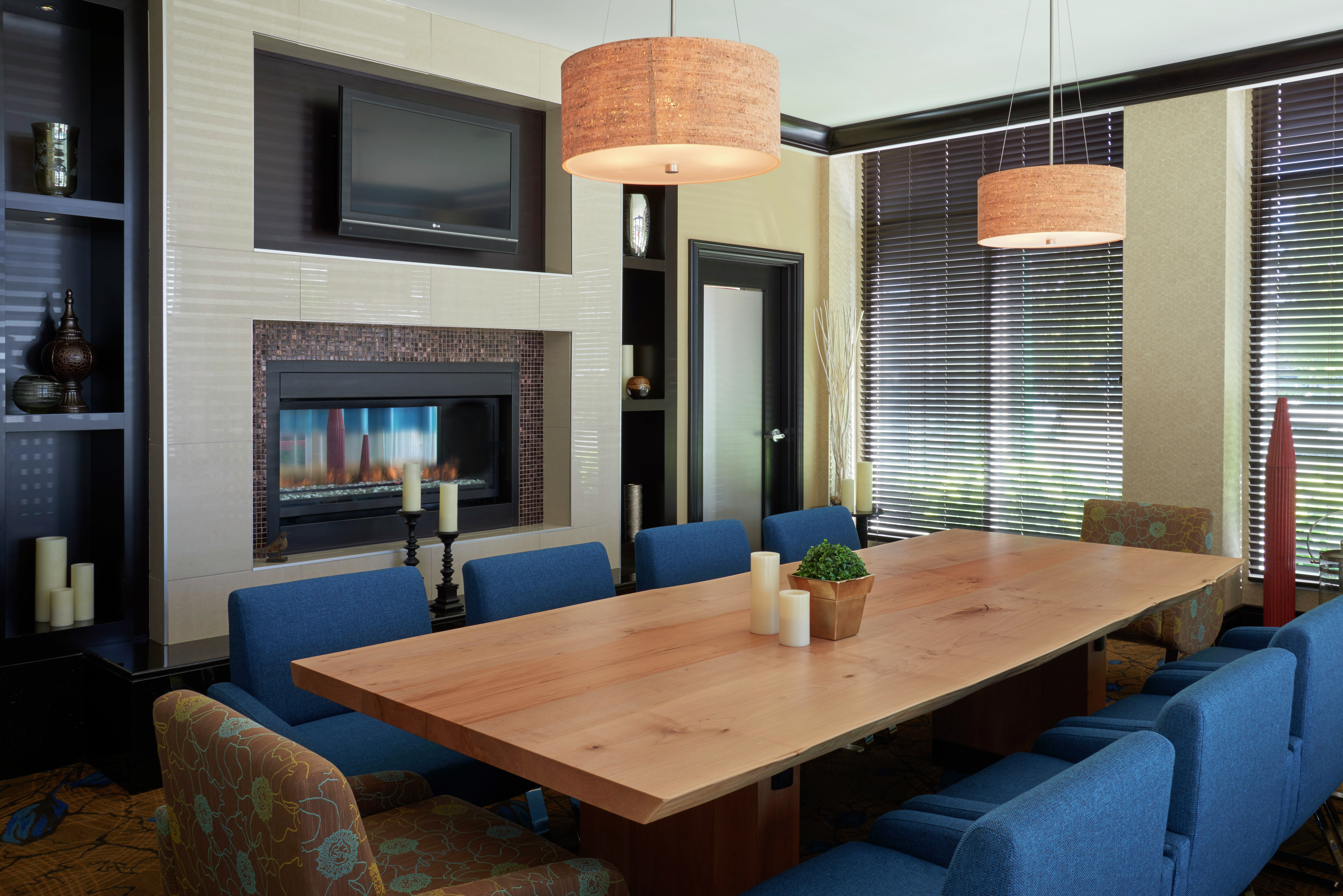 Seating for 10 at Large Wooden Table in Meeting Room With TV, Fireplace, and Large Windows