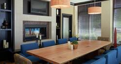 Seating for 10 at Large Wooden Table in Meeting Room With TV, Fireplace, and Large Windows