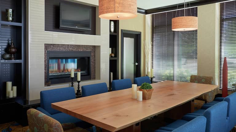10 chaises à une grande table en bois dans une salle de réunion avec téléviseur, cheminée et grandes fenêtres