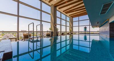 Indoor swimming pool with floor to ceiling windows and views of the city and outdoors