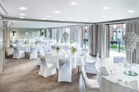 Event Space with White Linens, Covered Chairs, Tall Centerpieces with Doors Open to Terrace